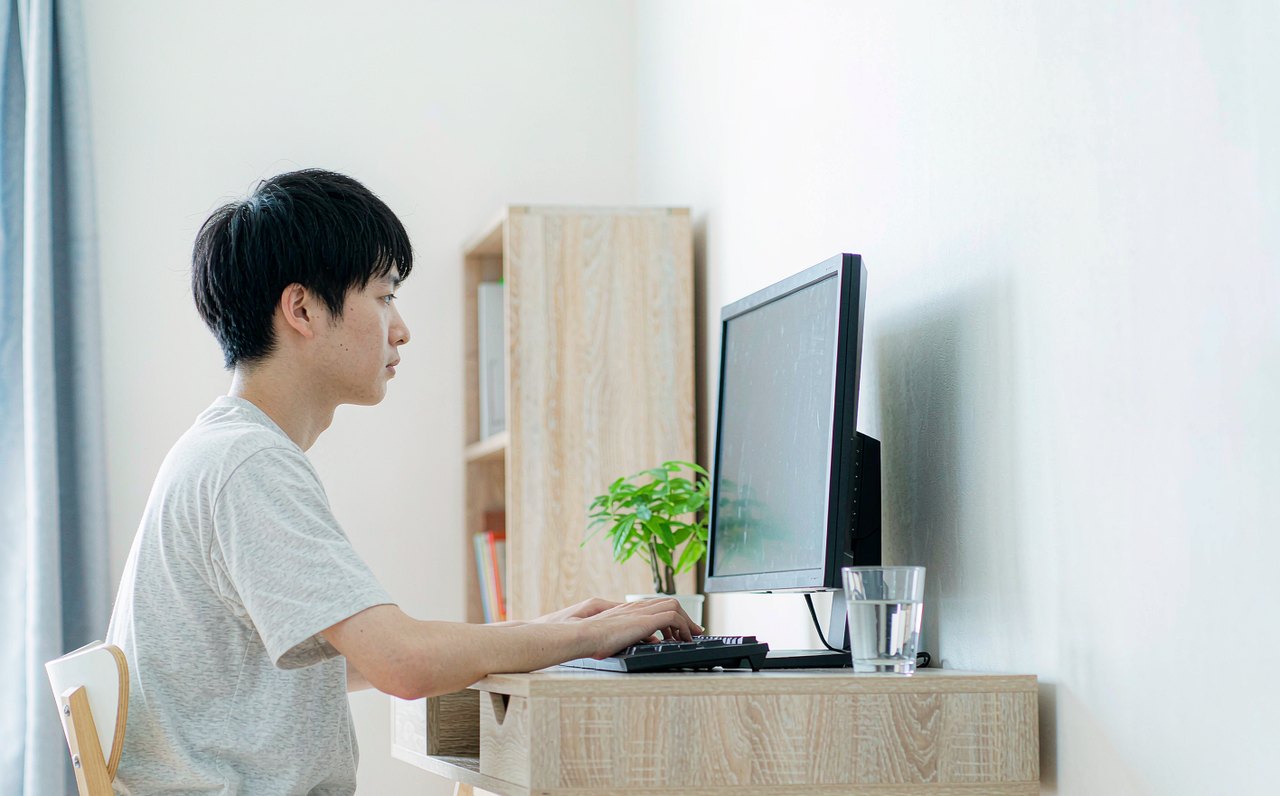 A gamer sitting upright at a well-lit desk with the monitor at eye level and forearms resting neutrally on the desk