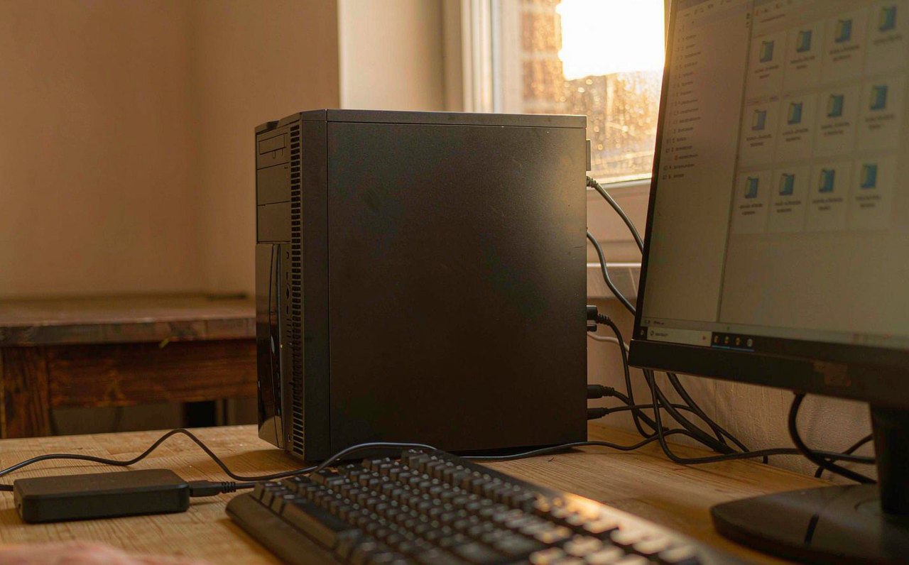 A desktop PC with an external backup drive connected, used to copy game save files before resolving a Steam Cloud sync conflict
